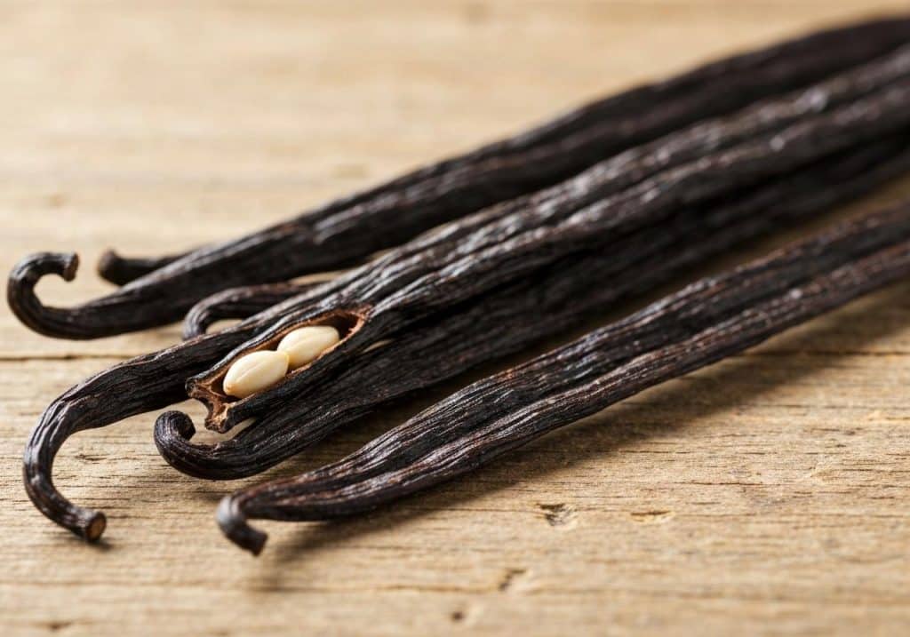 Gousses de vanille noires séchées sur fond bois